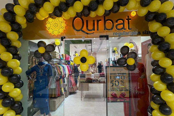 Store entrance with 'Qurbat' branding, balloons, and a discount sign.